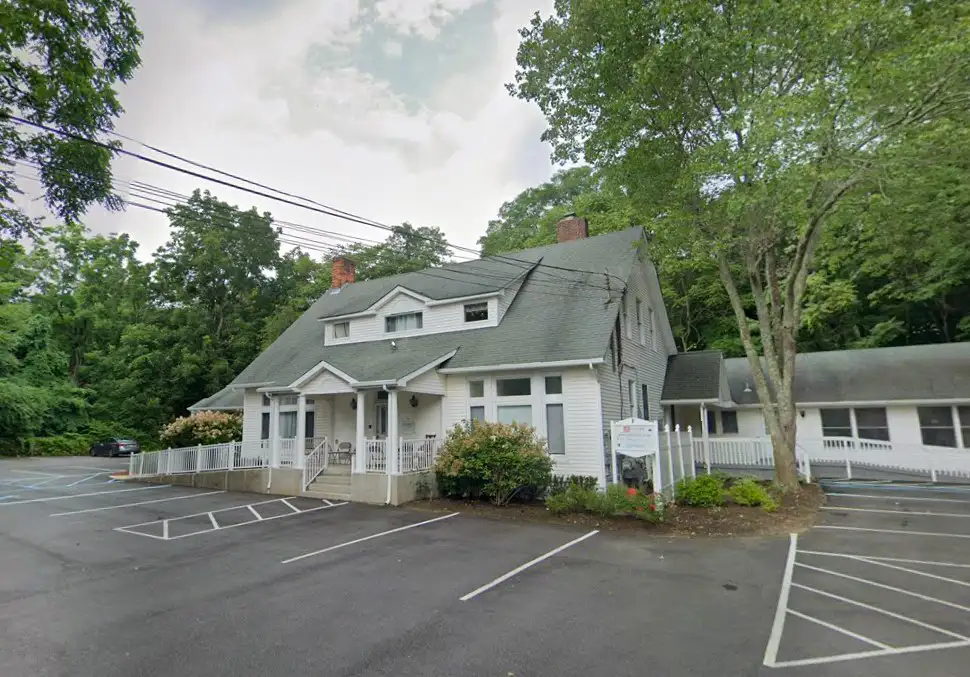 Building with a parking area and trees surrounding it, creating a natural environment.