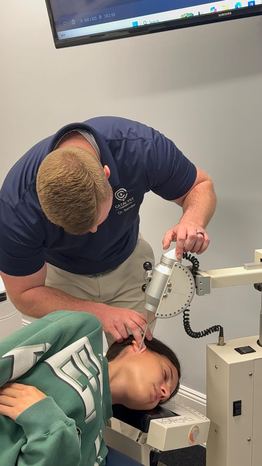 A woman receives chiropractic treatment from a man in a clinical setting.